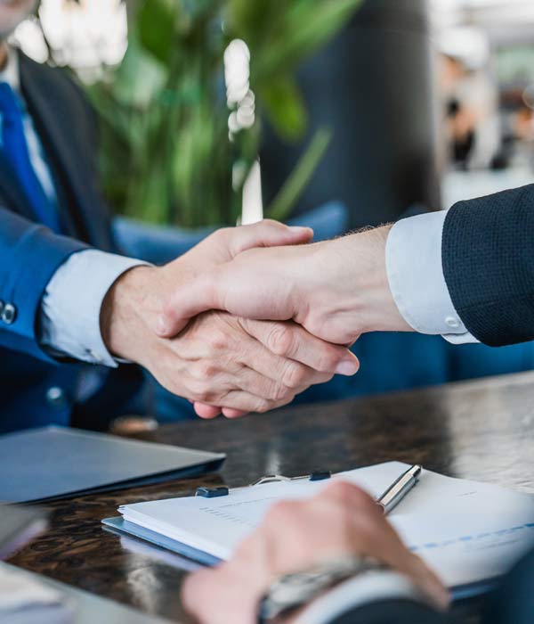 Two business professionals shaking hands across a conference table in Phoenix, AZ