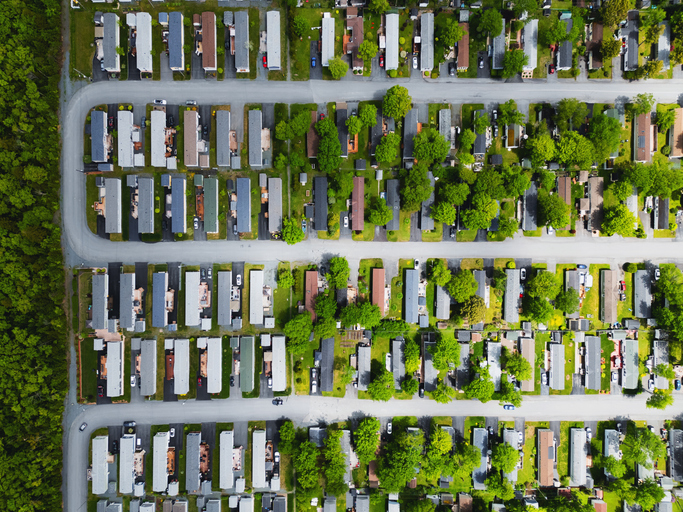 Aerial view of mobile home park in Phoenix, AZ, showing insured homes, roads, and greenery under homeowners coverage.