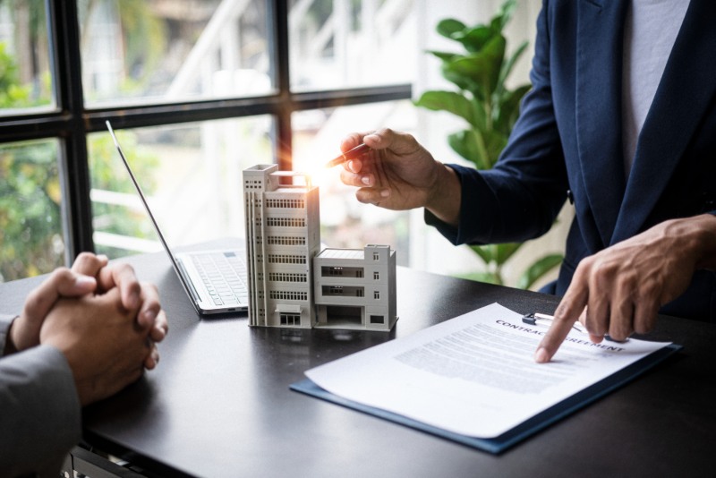 Professional pointing at a signed insurance document while holding a pen next to a small building in Glendale & Surprise, AZ